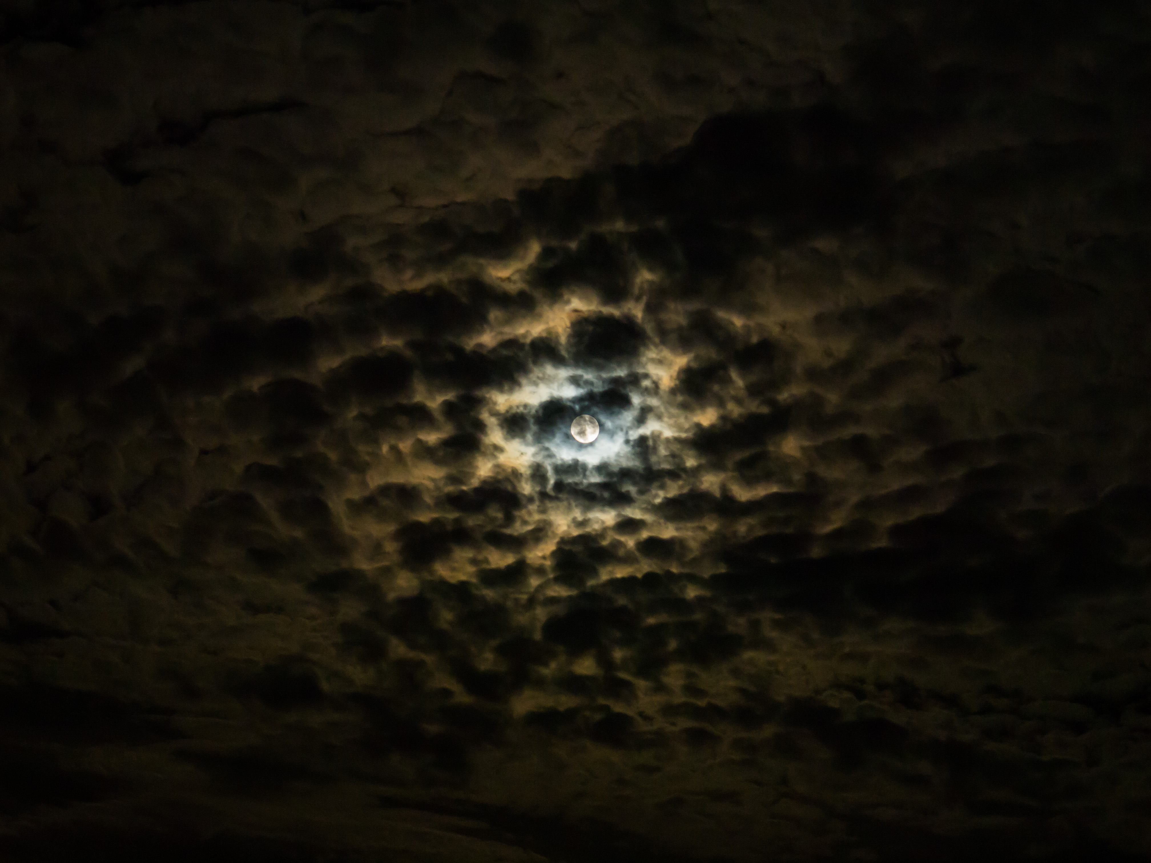 夜色中云层后的月亮，云是黑色和橙色